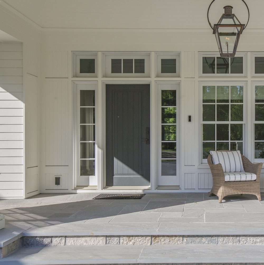 Gorgeous front porch with dark colored front door surrounded by windows
